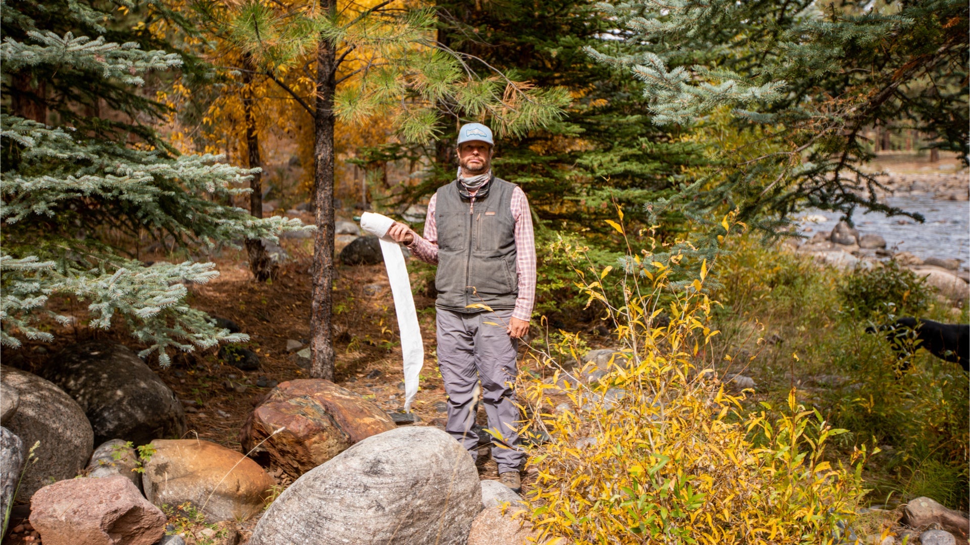 A man holding toilet paper in the backcountry.
