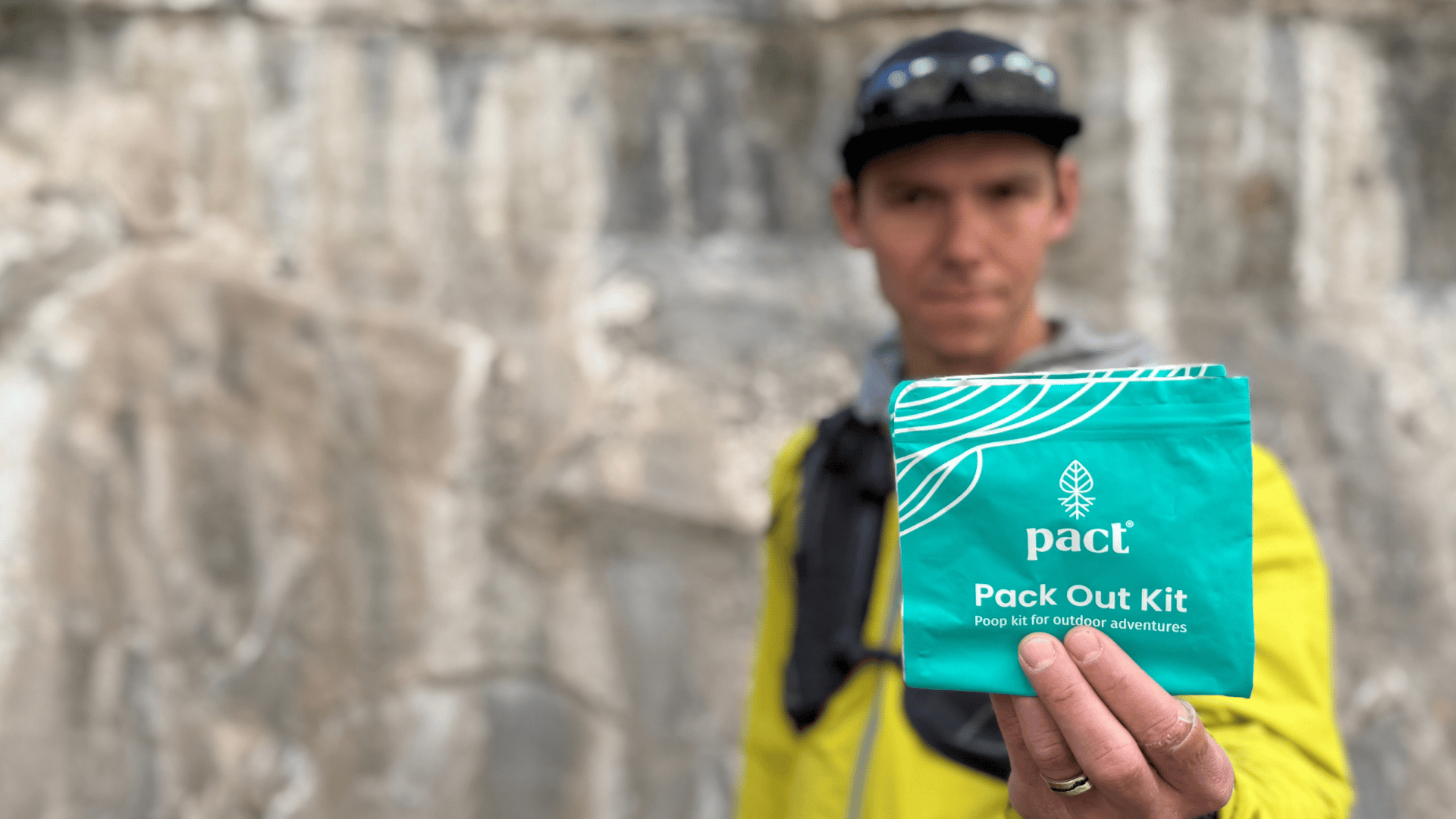 A man holding a PACT Pack Out Kit which make carrying out your poop in the backcountry easy. They’re durable, seal in odors, and include everything you need to feel clean.