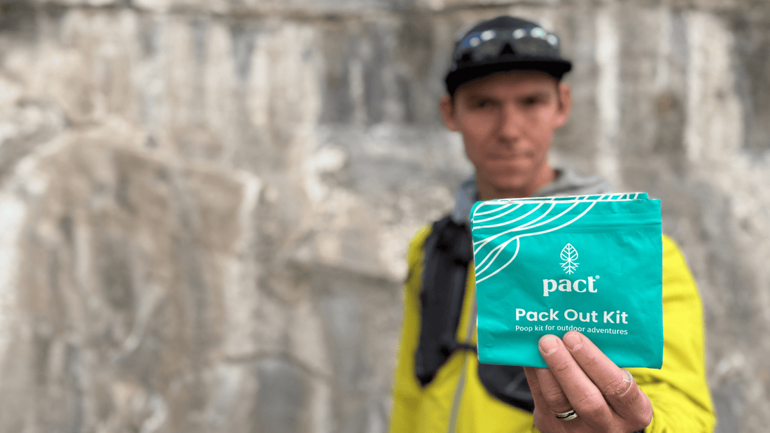 A man holding a PACT Pack Out Kit which make carrying out your poop in the backcountry easy. They’re durable, seal in odors, and include everything you need to feel clean.